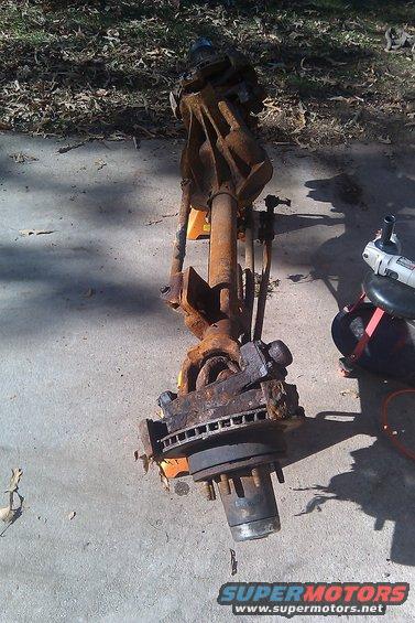 rusted front axle assembly with brake rotor and hub, resting on concrete