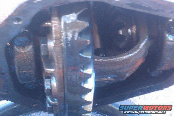 Close-up of differential gears with oil, showing wear and metal components