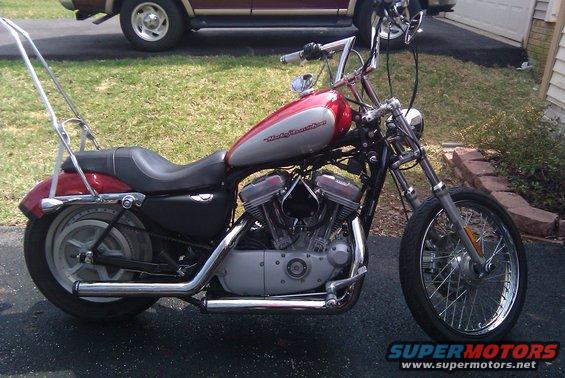 Side view of a red and silver Harley-Davidson Sportster Custom motorcycle parked outside