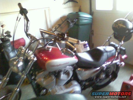 Red and silver 2004 Harley-Davidson Sportster Custom motorcycle parked indoors, viewed from the front-right