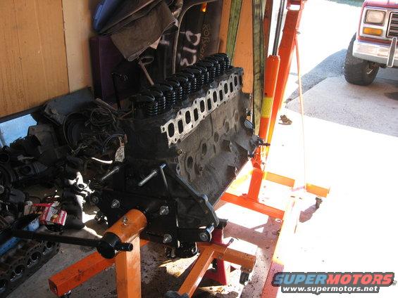 Engine on an orange engine stand, with a red Ford truck in the background