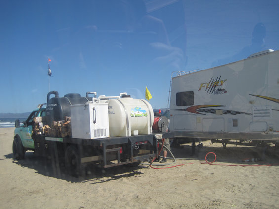 Truck with water tanks and a trailer on a sandy beach