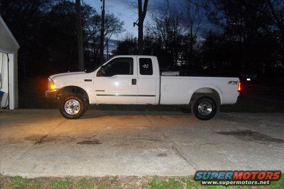 White 2000 Ford F-250 truck, side view, parked on concrete driveway at dusk