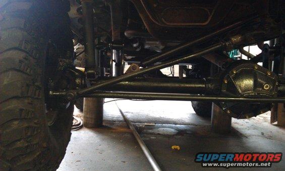 Undercarriage view showing suspension components, large tire, and differential housing