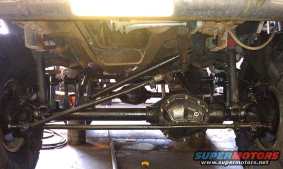 Underside view of a vehicle's drivetrain, showing the front axle, differential, and suspension components