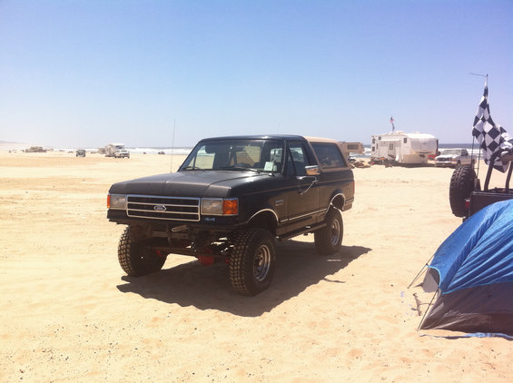 Black 1989 Ford Bronco with tan top on beach