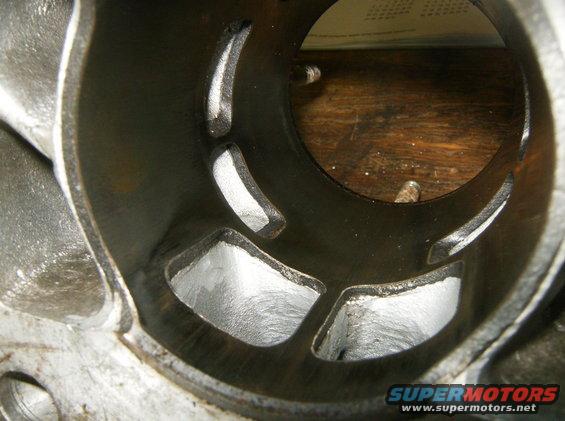 Engine cylinder interior with machined ports and a wooden surface in the background