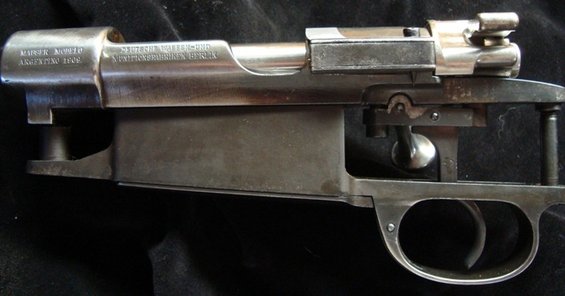 Rifle receiver with visible text 'MAUSER MODELO ARGENTINO 1908' and 'DEUTSCHE WAFFEN-UND MUNITIONSFABRIKEN BERLIN'