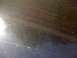 1985 Ford Mustang - Close-up of a dark, reflective surface, possibly a car's paint, showing scratches and light glare.