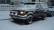 1988 Ford Bronco - A dark Ford Bronco sits parked on a snowy street, partially covered in snow.