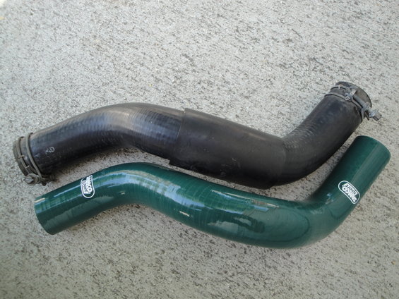 Green silicone and black rubber radiator hoses on concrete. Silicone hose has 'Samco Sport' logo