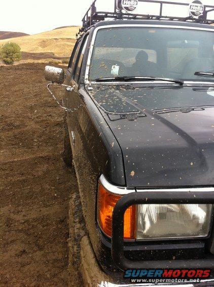 Mud-splattered black SUV with roof rack, driving off-road