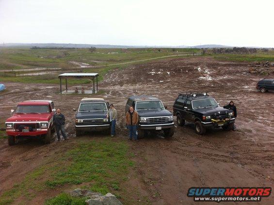 Four SUVs and one truck parked on a muddy hill under an overcast sky