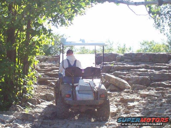 Golf cart with a person driving on a rocky trail