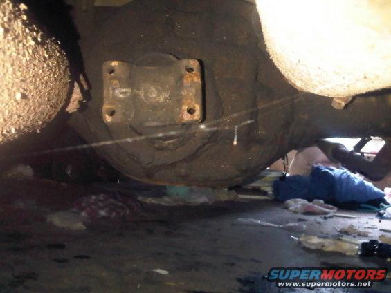 Close-up of a vehicle's rear differential and suspension components, with debris on the ground below