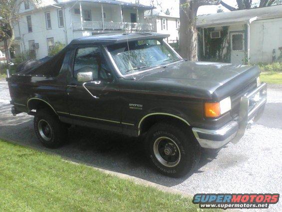 1988 Ford Bronco with a dark green body and a soft top cover over the rear