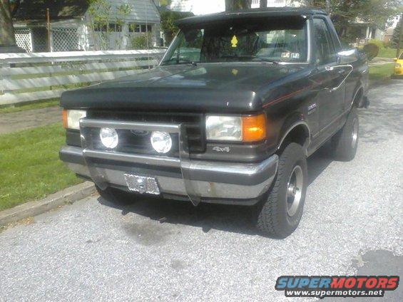 Black Ford Bronco with a brush guard and fog lights parked on a street