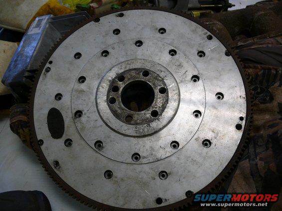 Metal flywheel with bolt holes and gear teeth around the edge