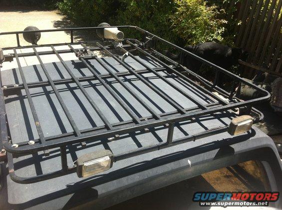 Roof rack with two round lights and a spotlight mounted on top of a dark vehicle