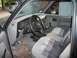 1994 Ford Explorer - The interior of a dark blue pickup truck, plaid seats and a dashboard that appears to be from 1994. Other vehicles are visible through the…
