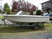 1993 Tracker Tournament - A white boat with an outboard motor is parked on a trailer in front of a house.