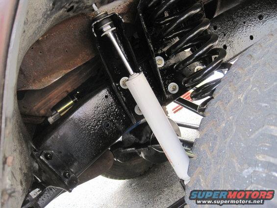Close-up of vehicle suspension with black coil spring and white shock absorber