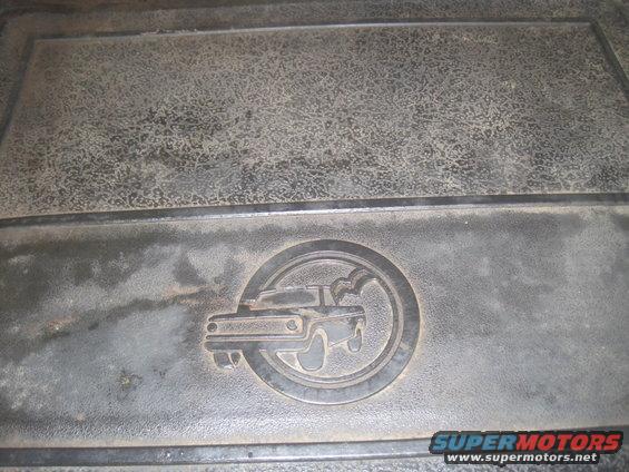 Embossed emblem of a truck inside a circle on a dark floor mat
