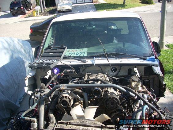 Truck with front end removed, showing engine and parts. California license plate visible