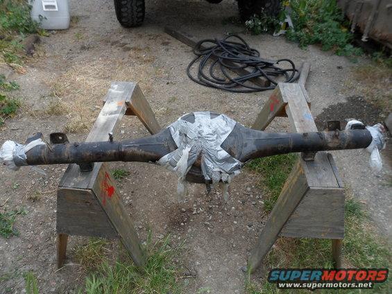 Differential axle covered in tape, resting on sawhorses outdoors