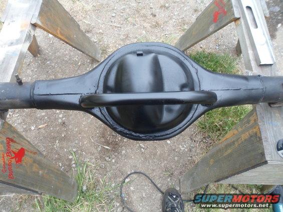 Black rear axle differential housing on wooden sawhorses. "Genuine Burro Brand" logo visible on wood