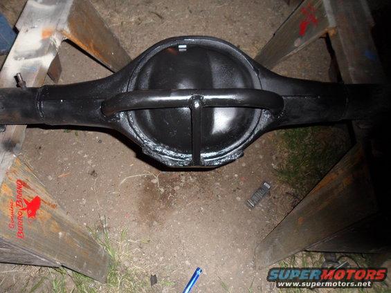 black rear axle differential assembly on wooden sawhorses, with text on wood reading 'Genuine Burro Brand'