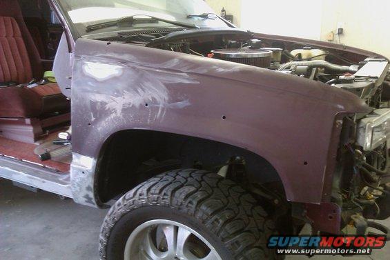 Maroon SUV fender and interior under repair, showing bodywork and engine components