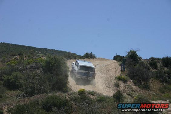 White 1991 Ford Bronco driving down a dusty hill