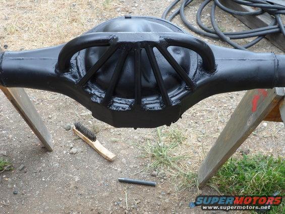 Black painted Ford rear axle differential housing on sawhorses with a brush nearby