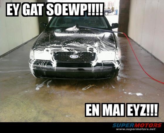 Front view of a black sedan being washed with soap and water. A hose is visible