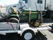 1966 Ford Bronco - A green John Deere riding mower is secured to a trailer, parked next to a white semi-truck.
