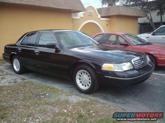 Black 2001 Ford Crown Victoria parked outside a building, with a red car behind it