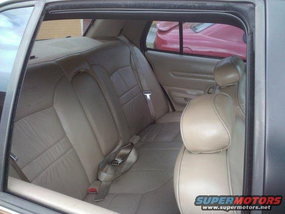 Car interior showing tan leather rear seats and a red car visible through the window