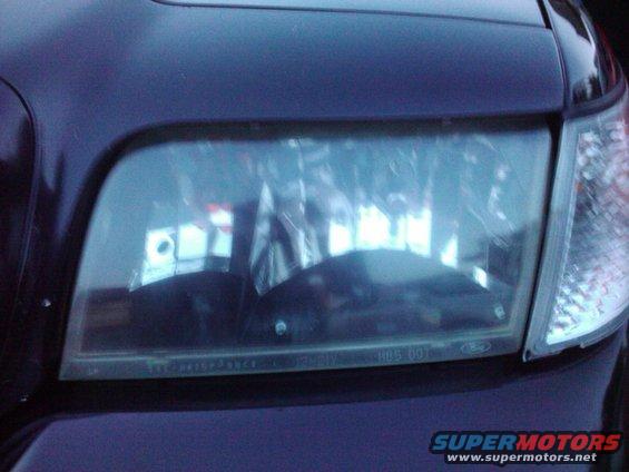 Close-up of a 2001 Ford Crown Victoria headlight assembly. Shows the Ford logo and DOT markings