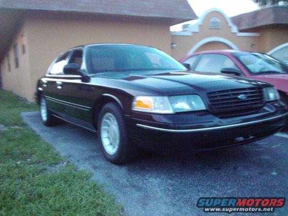 Black 2001 Ford Crown Victoria parked on asphalt, front 3/4 view. Another car is visible behind it