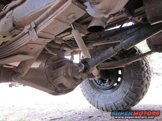 Underside view of a 4x4's rear axle, leaf springs, driveshaft, and tire