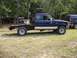 1994 Ford Explorer - A blue Ford Ranger pickup truck with a custom flatbed is parked outdoors next to an SUV.
