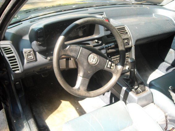 Interior shot of a Honda Prelude, showing the steering wheel, dashboard, and gear shifter
