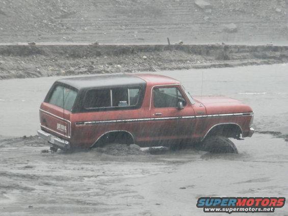 Red 1978 Ford Bronco stuck in mud, side view