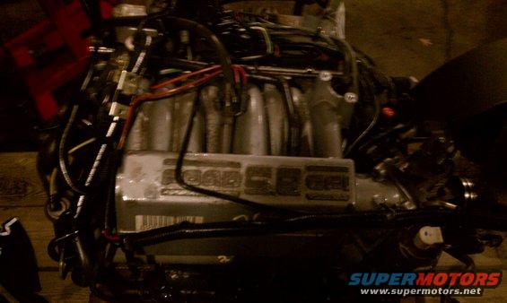 Engine with visible wiring and intake manifold. Text visible on a component