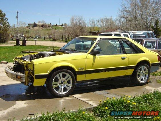 Yellow 1979 Ford Mustang coupe, hood open, front bumper removed