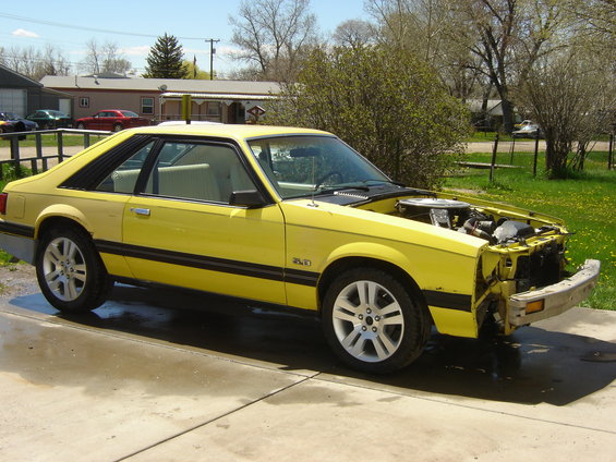 Yellow 1979 Ford Mustang coupe, hood open, parked on driveway