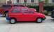 1991 Ford Festiva - A red hatchback is parked in a lot with other vehicles nearby.