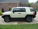 2010 Toyota FJ Cruiser - Side view of a white 2010 Toyota FJ Cruiser parked on a paved surface with grass and a house in the background.