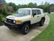 2010 Toyota FJ Cruiser - A tan Toyota FJ Cruiser is parked on a concrete driveway in front of a residential house.